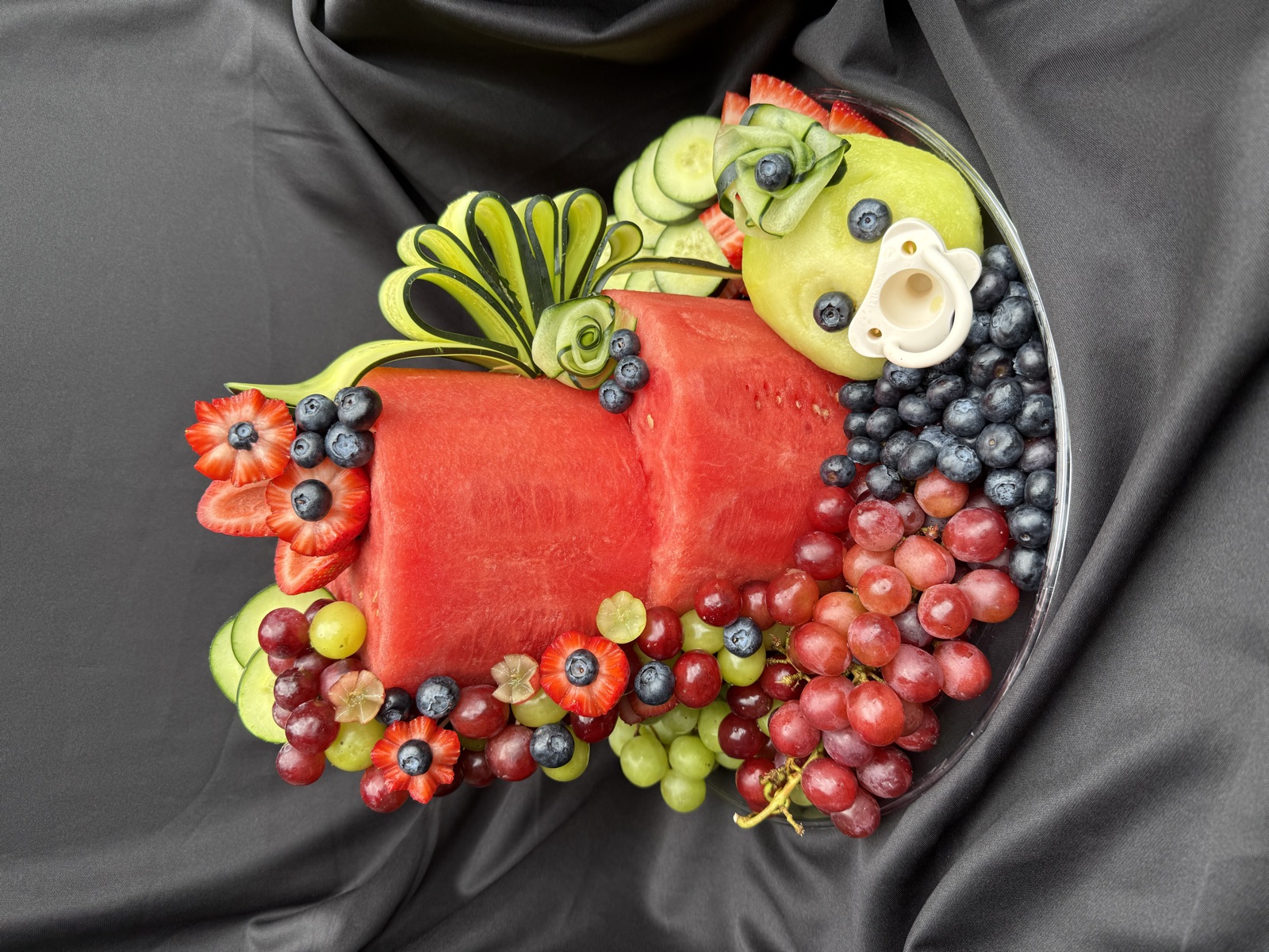 Baby-themed two-tier watermelon cake with a small fruit platter around it