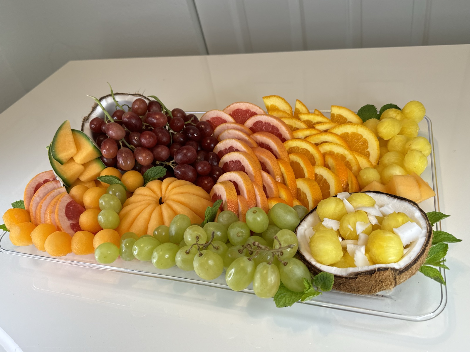 Fall theme fruit platter with coconut bowls of melon balls, citrus slices, grapes and carved cantaloupe