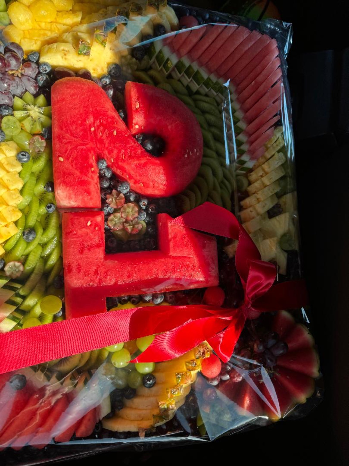 Jumbo fruit platter with carved watermelon numbers and a red ribbon