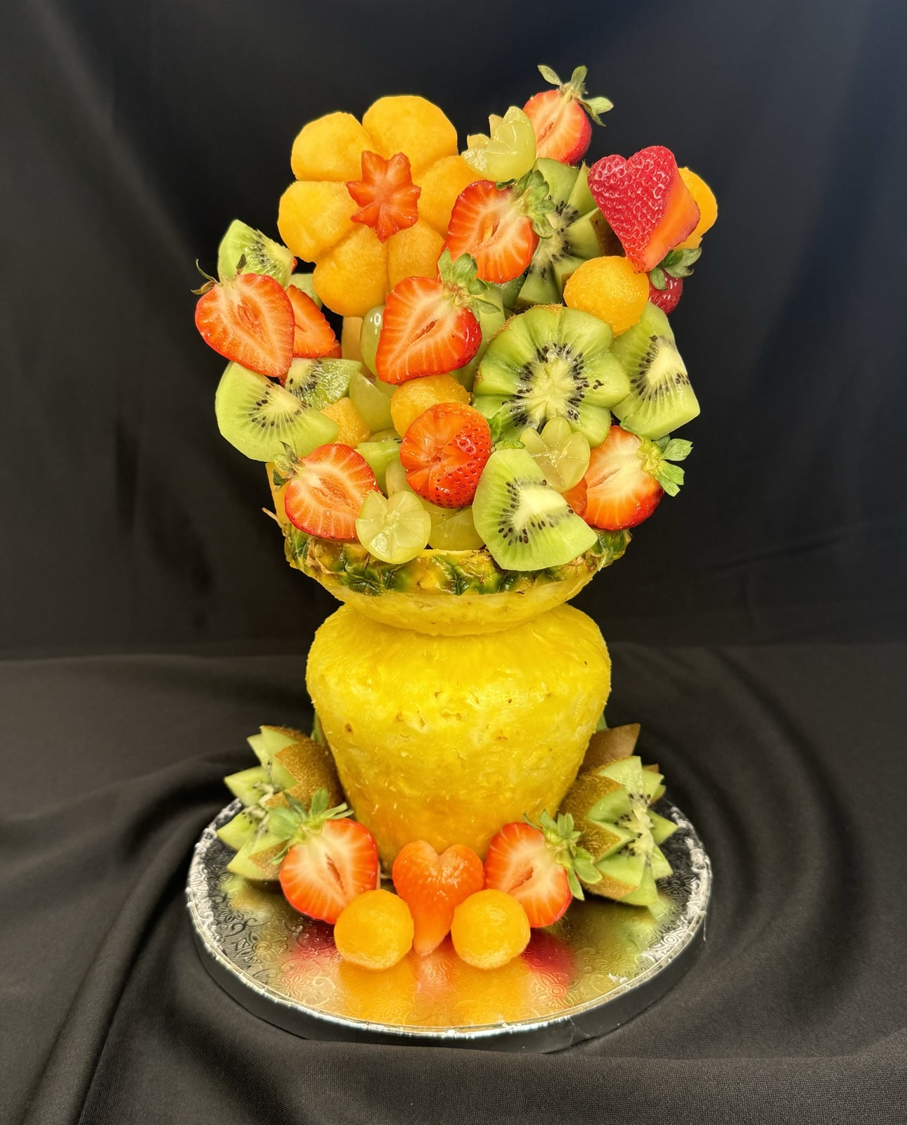 Carved pineapple vase arrangement filled with strawberries, kiwi, melon and grapes