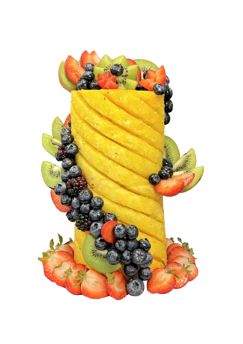 A carved pineapple fruit tower decorated with fresh berries, kiwi, and citrus, handmade by Delicious Designs